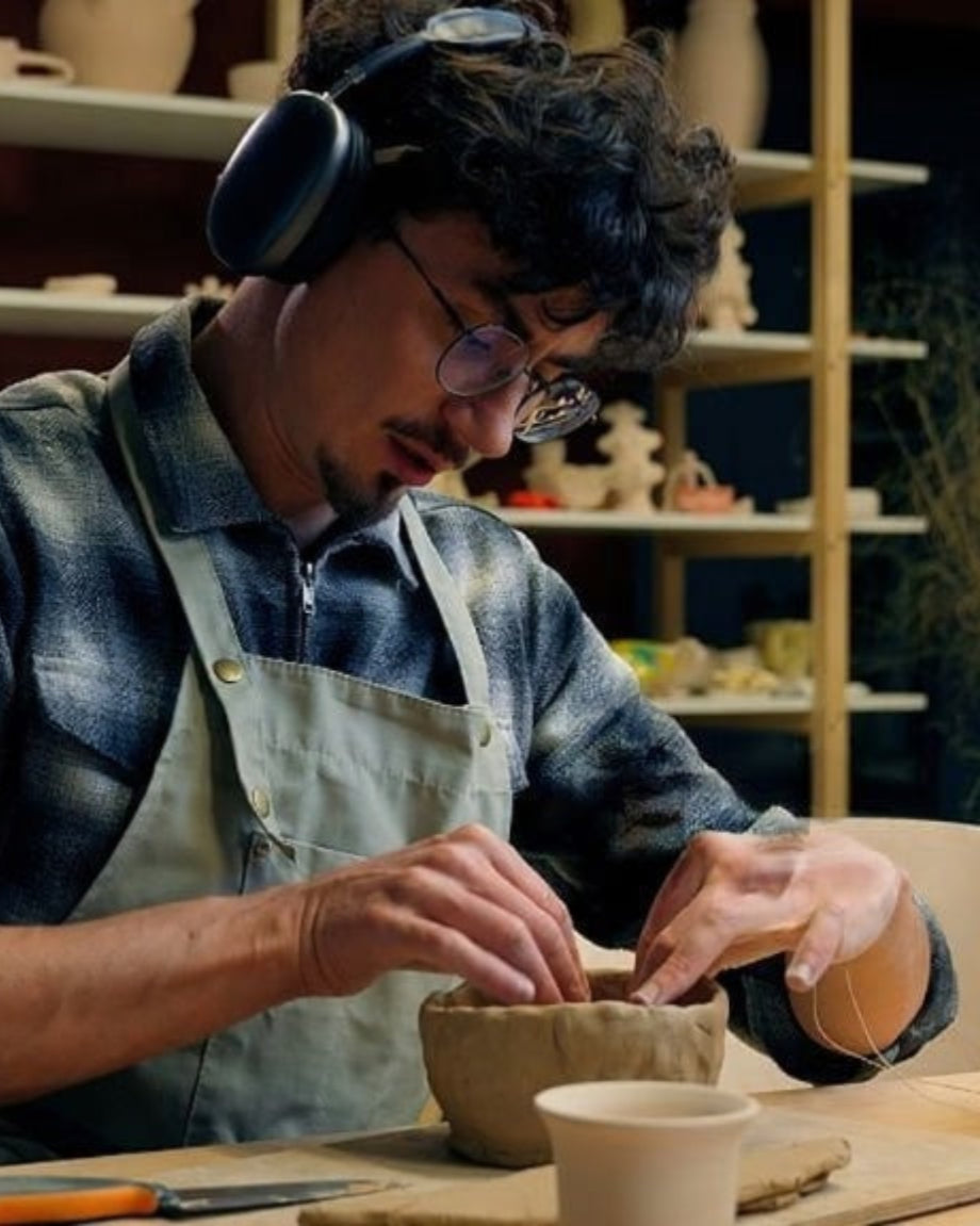 Person working with pottery in a workshop setting