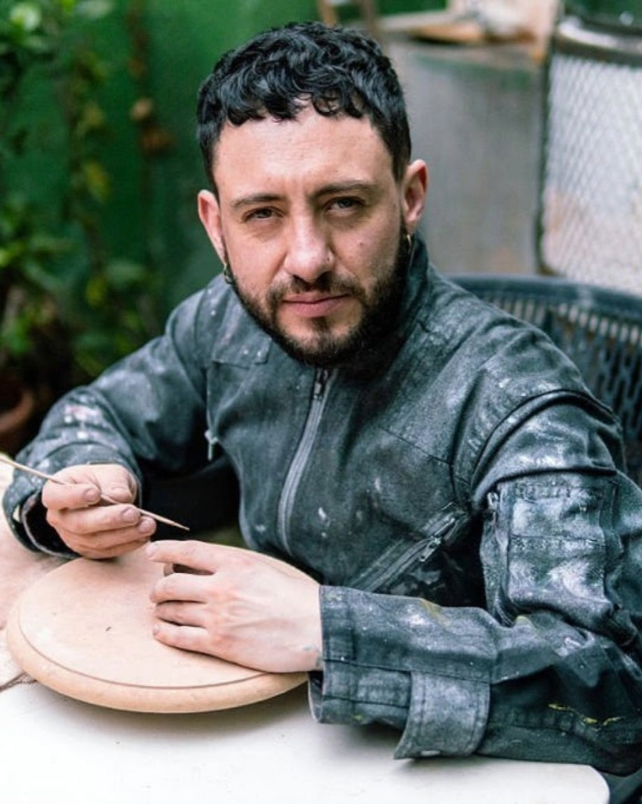 Man working with clay at a pottery wheel outdoors