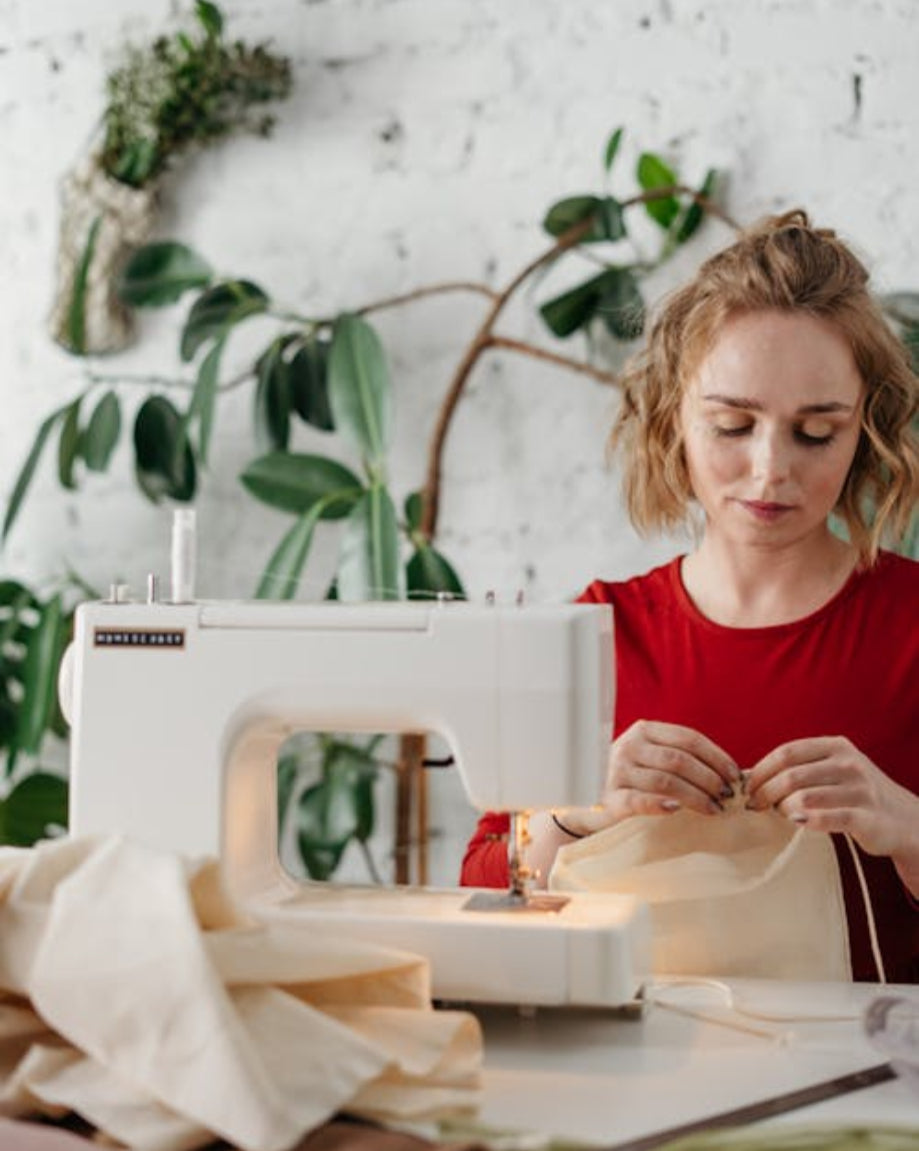 Woman working on a sewing project with a sewing machine in a home setting.