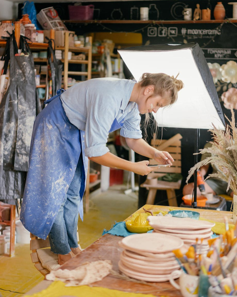 Person working with clay on a pottery wheel in a studio setting.