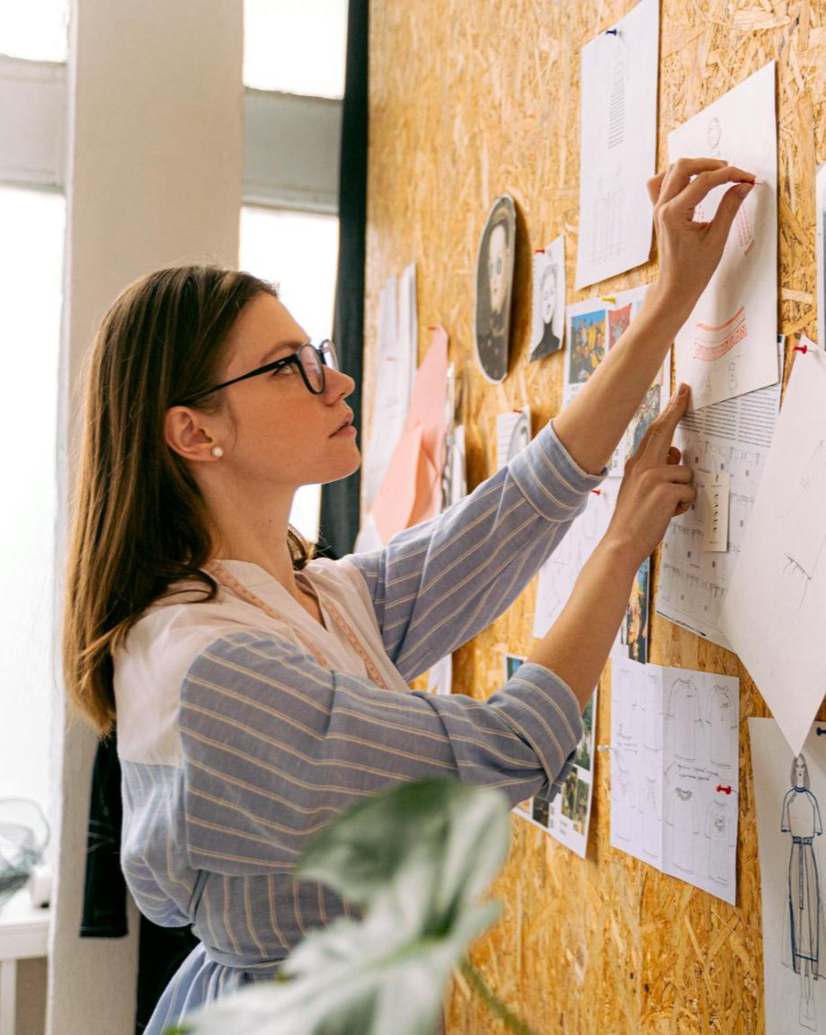 Woman looking at pinned papers on a cork board in an office setting