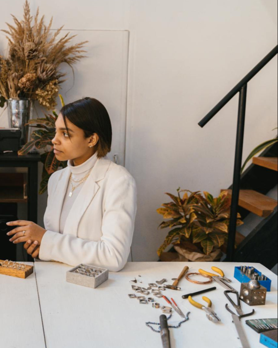 Two people in a workshop setting with tools and materials on a table.