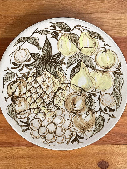Decorative plate with fruit design on a wooden surface
