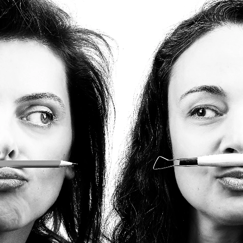 Two women holding makeup tools in front of their faces