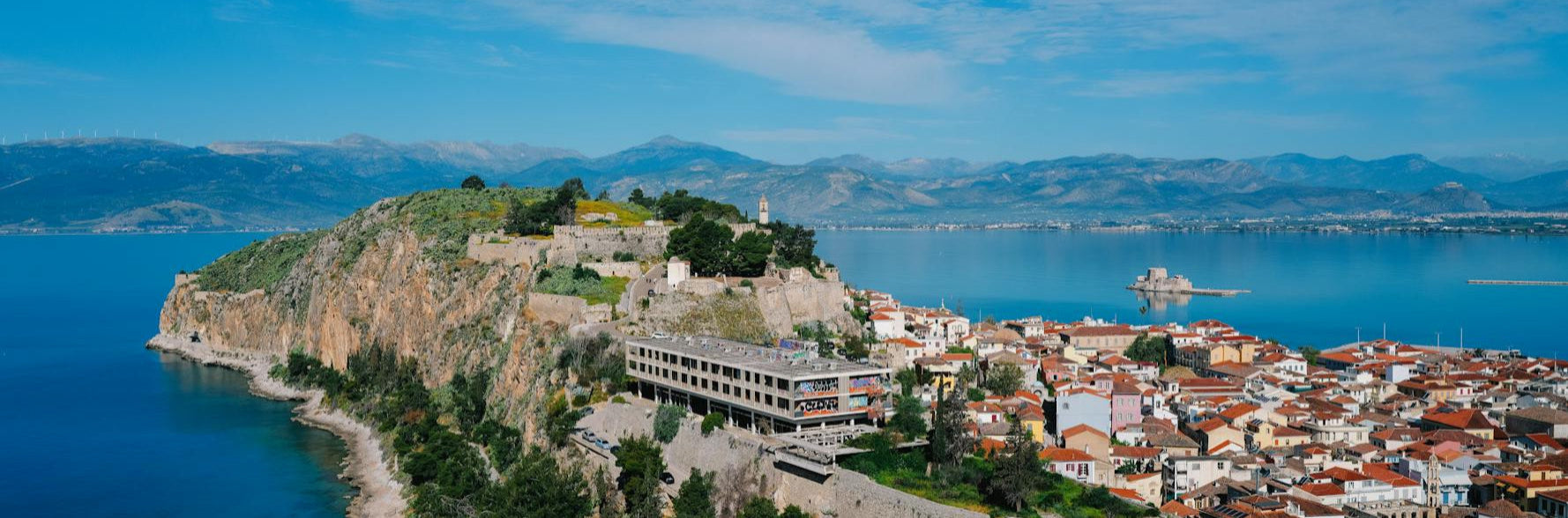 Cityscape on a hill overlooking a body of water with mountains in the background