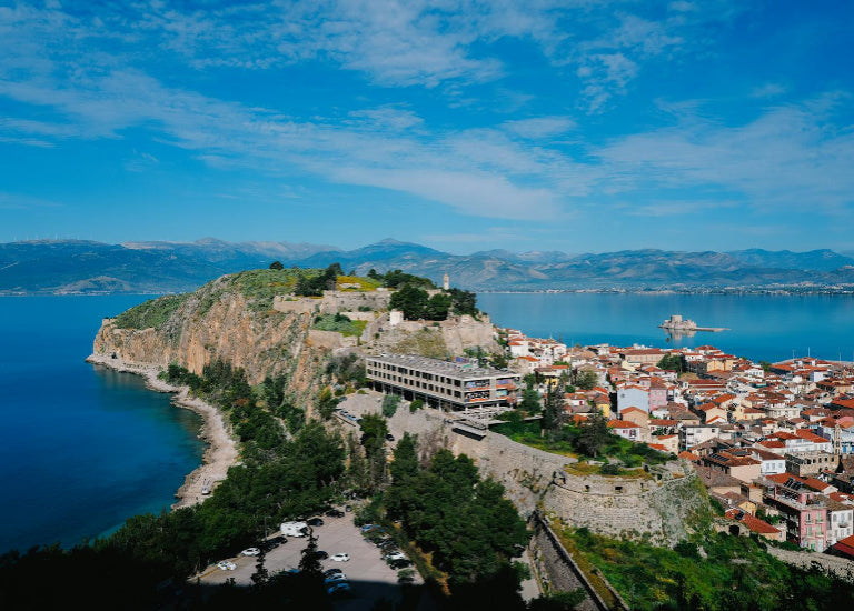 Cityscape on a hill overlooking a body of water with mountains in the background