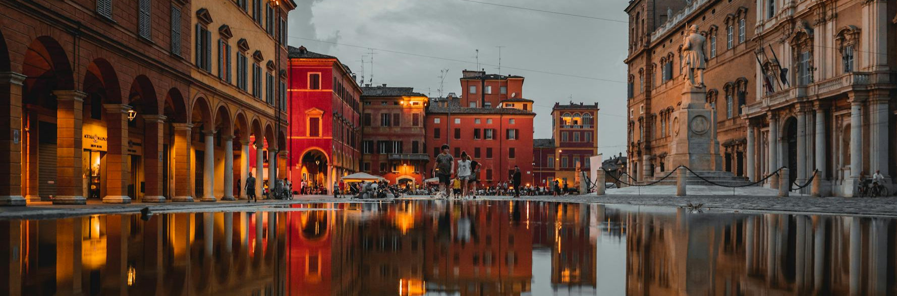 City street with buildings reflecting in water at dusk