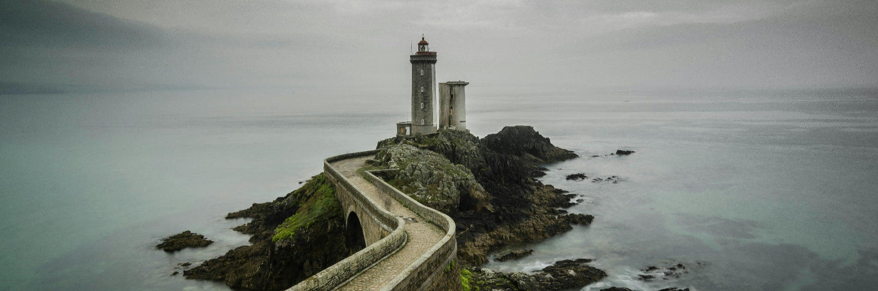 Lighthouse on a rocky island with a stormy sea and sky