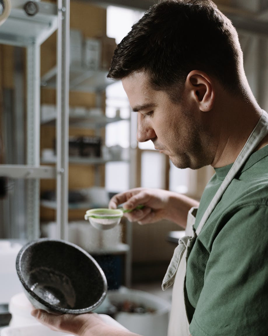 Man in a pottery studio examining a bowl