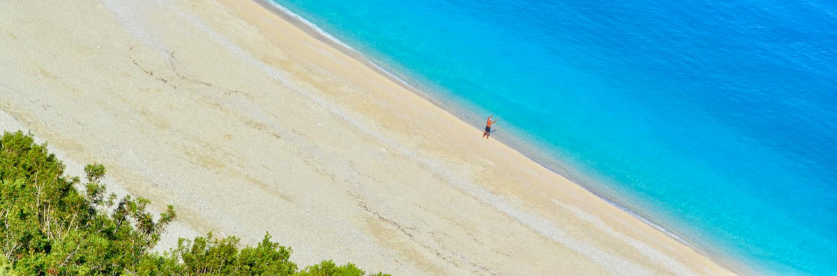 Beach with clear blue water and a person standing on the sand