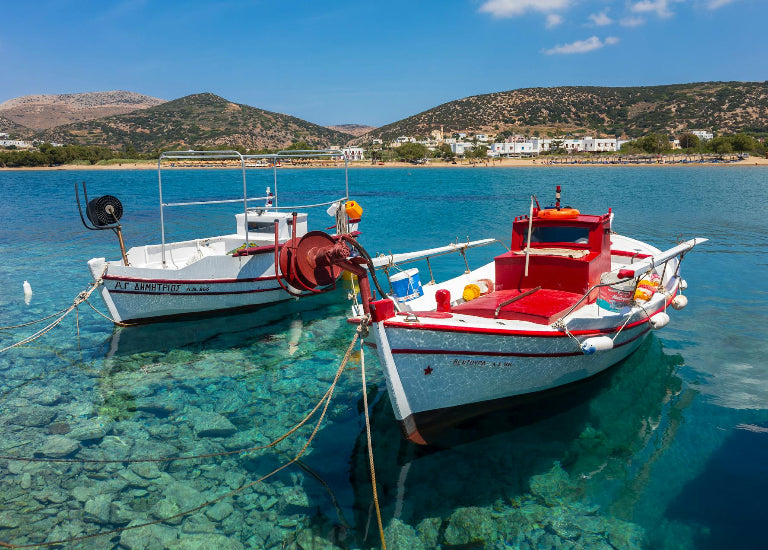 Two boats docked in clear blue water with a scenic background