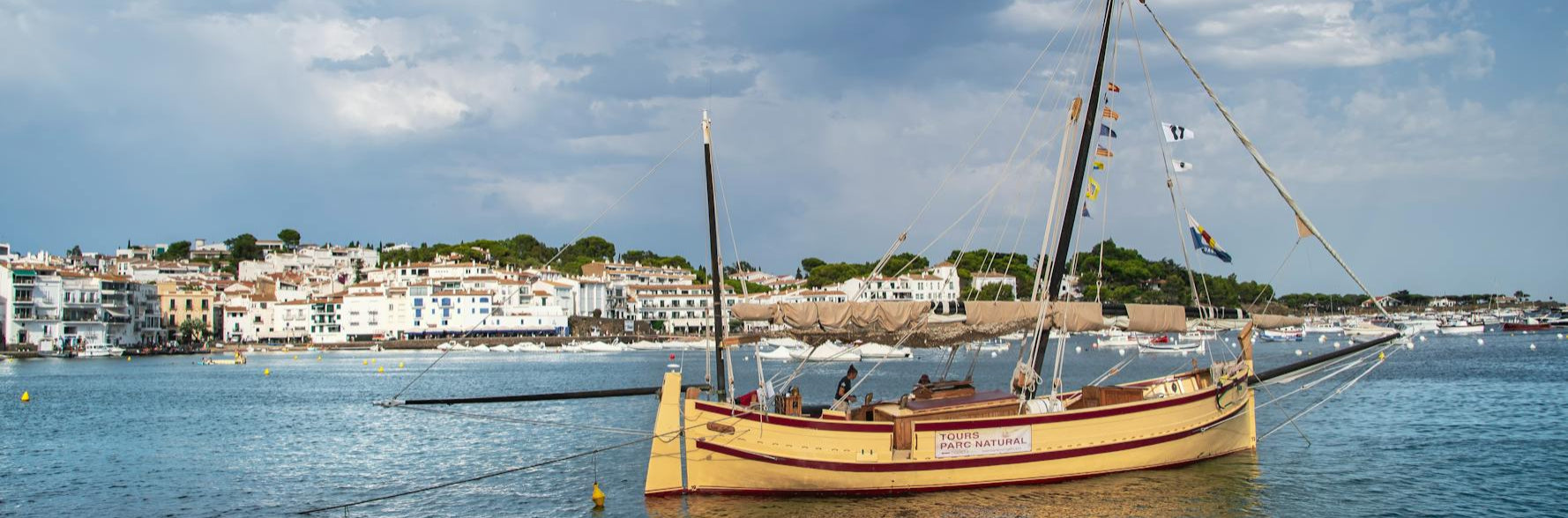 Traditional wooden boat on a body of water with a coastal town in the background