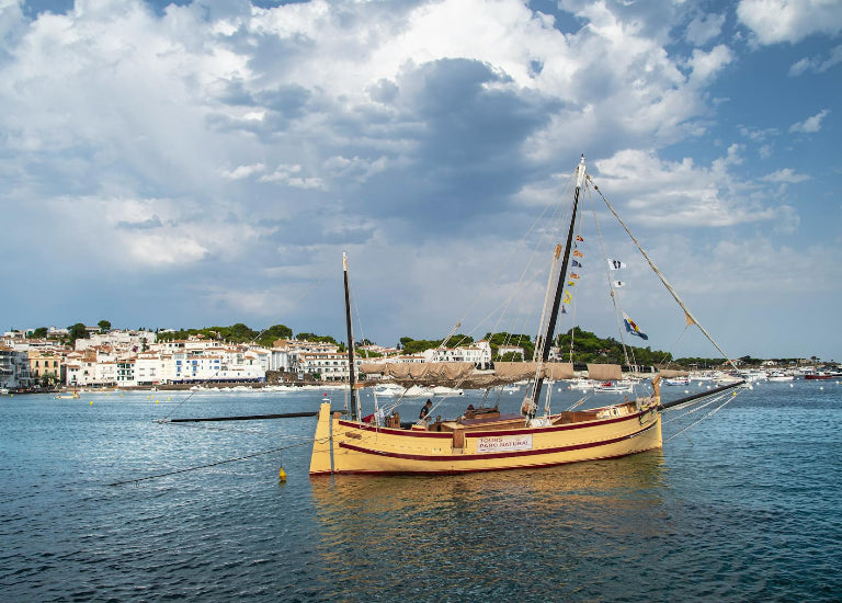 Traditional wooden boat on a body of water with a coastal town in the background
