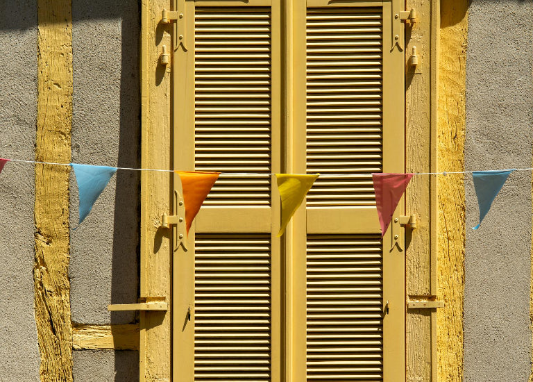 Yellow shutters with colorful triangular flags on a gray wall
