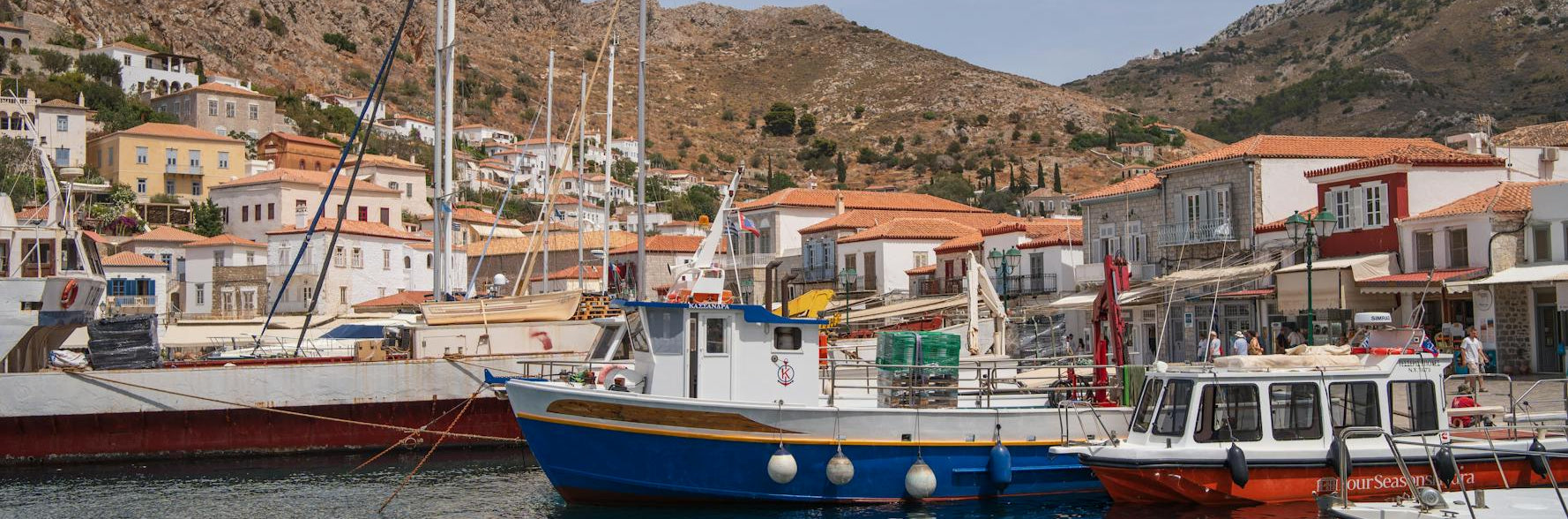Harbor scene with boats and buildings against a mountainous background