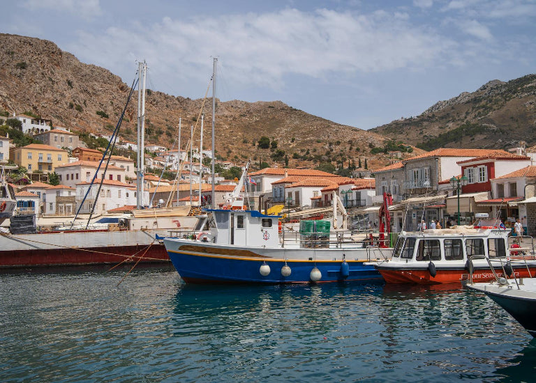Harbor scene with boats and buildings against a mountainous background