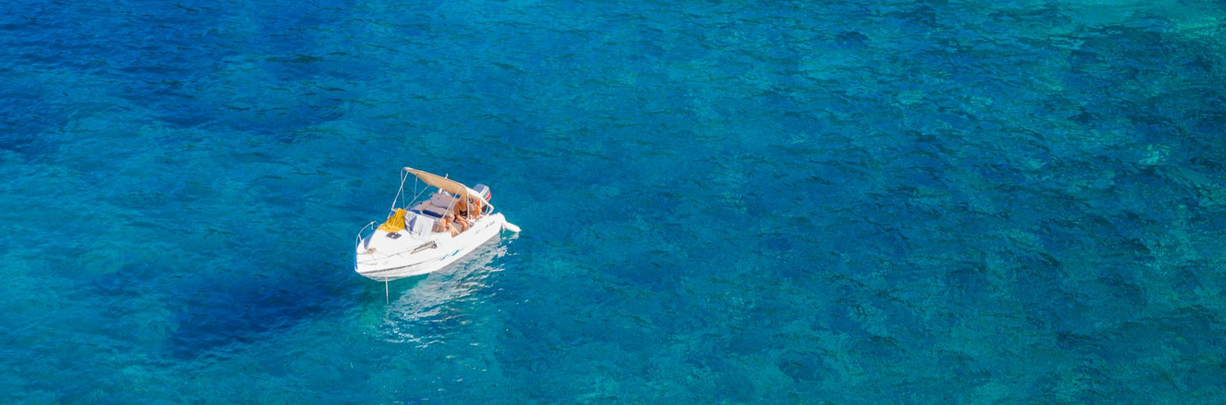 Small boat in the middle of a clear blue ocean