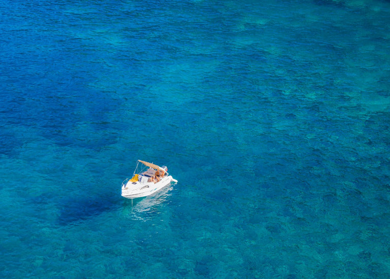 Small boat in the middle of a clear blue ocean