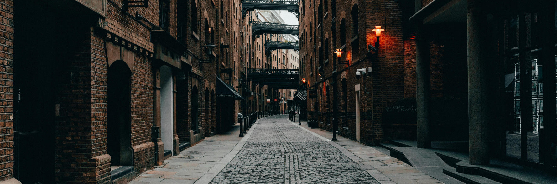 Cobbled street between brick buildings with a bridge in the background